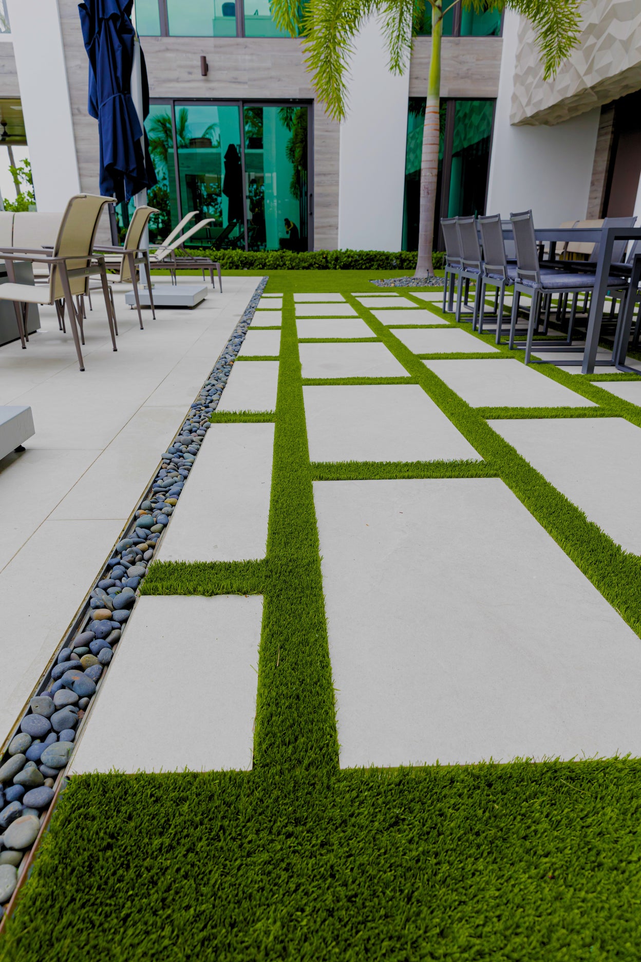 Outdoor patio with grassy pathways and chairs in a modern setting