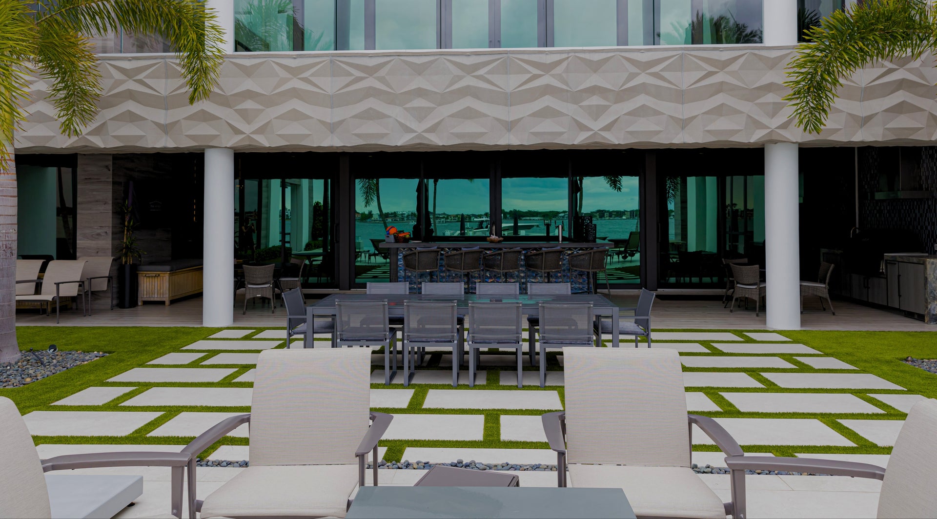 Outdoor seating area with chairs and tables in front of a modern building with large windows.