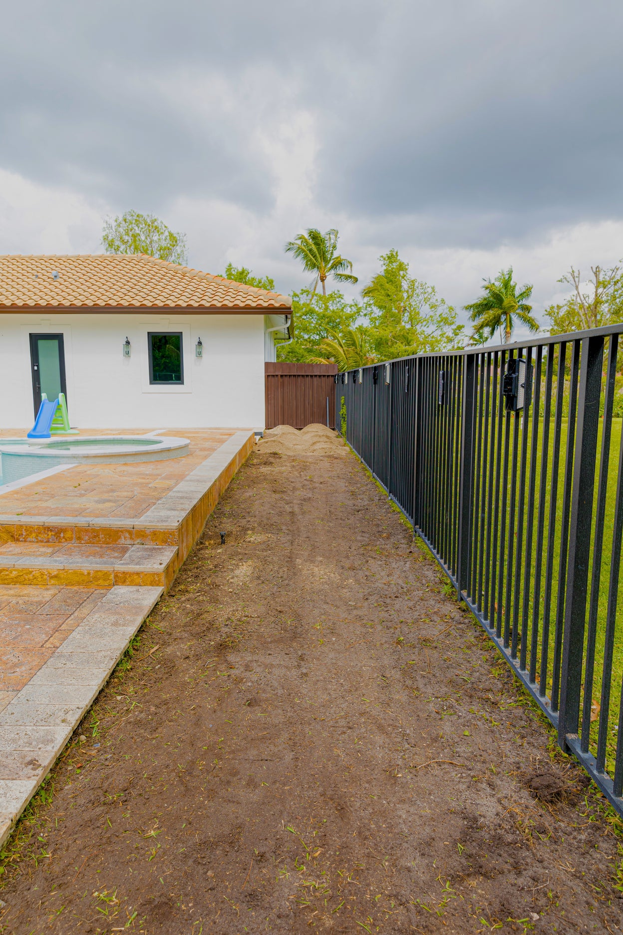 Pathway leading to a pool area with a house and trees in the background