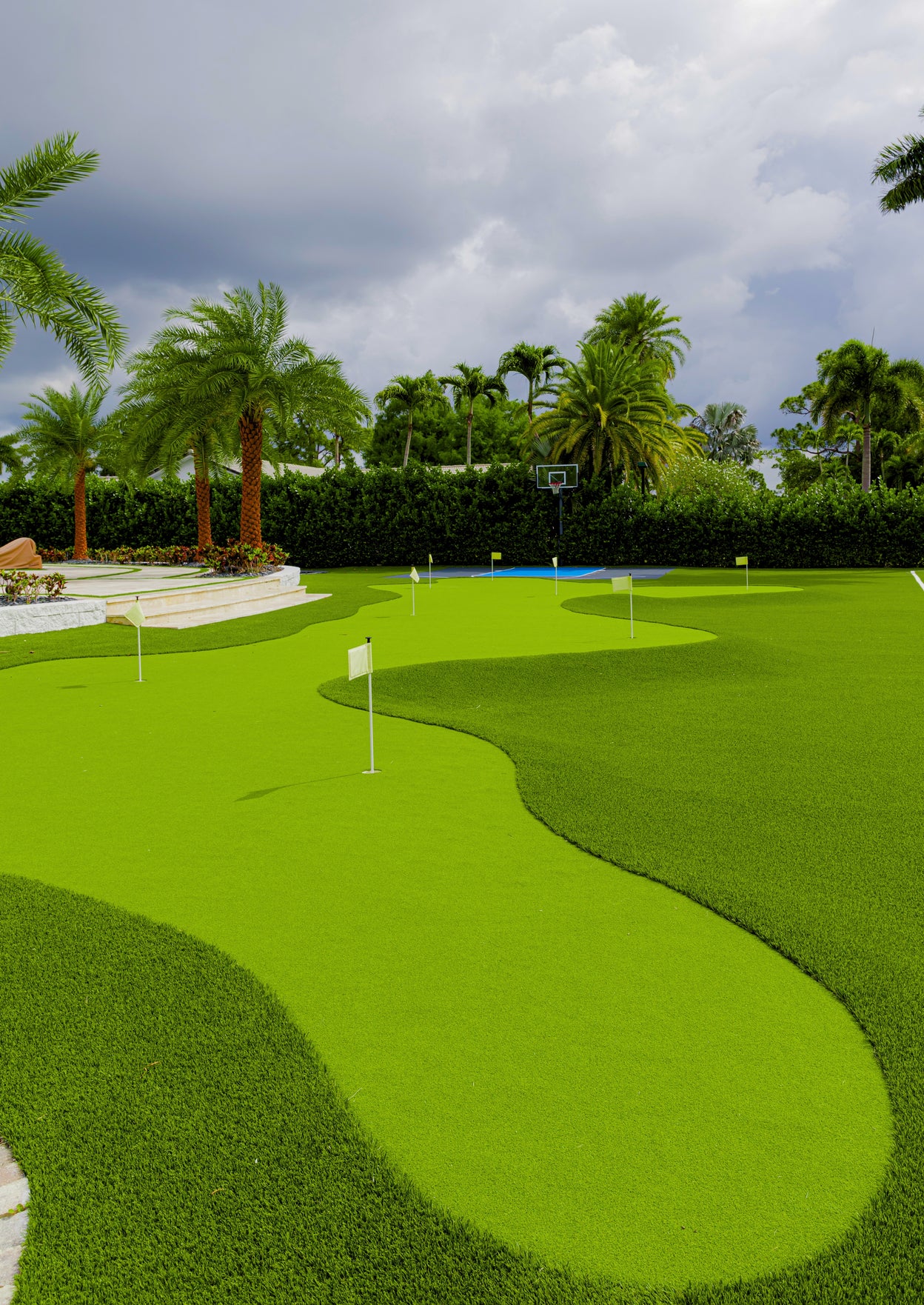 Golf course with green grass and palm trees under a cloudy sky