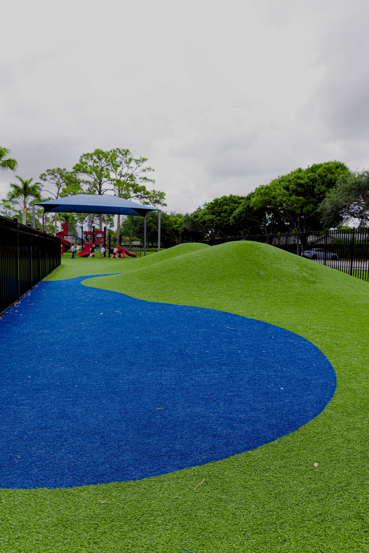 Playground with green and blue surface, trees in the background