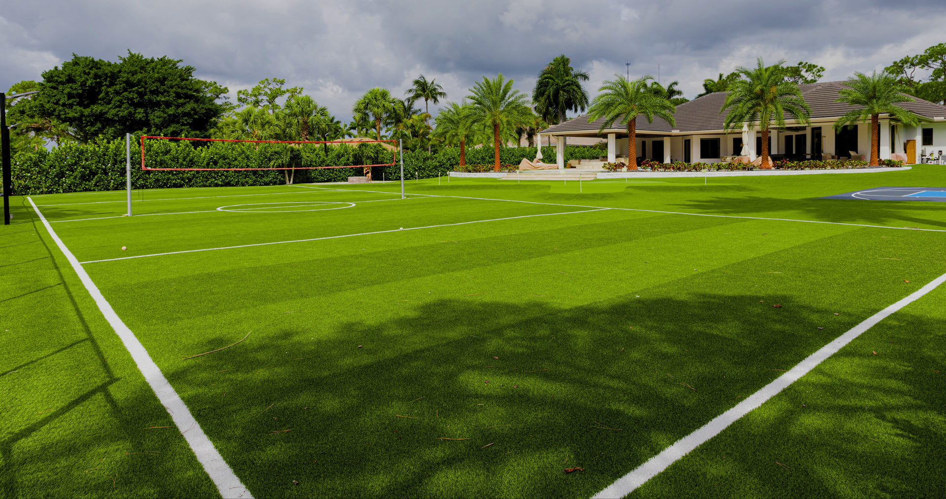 Tennis court with palm trees and a house in the background