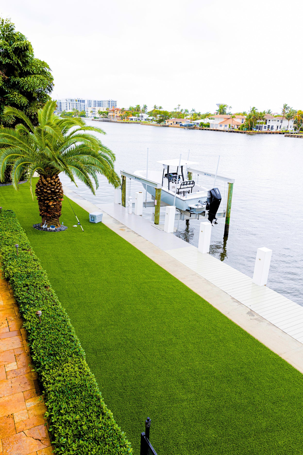Lush green lawn with a palm tree and dock in the background